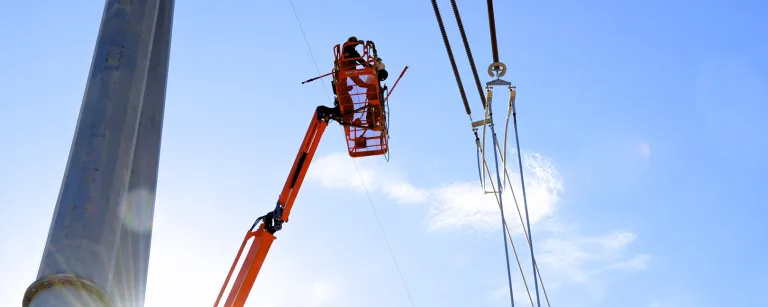 Worker on boom lift working on transmission tower