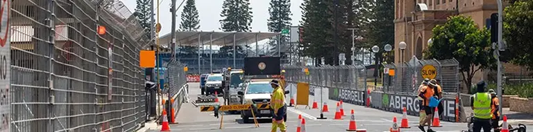 Workers installing pole barriers on a city street to enhance road safety and manage traffic flow.