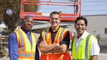 three men in ppe by scissor lift