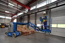 Worker on electric boom lift inside a warehouse