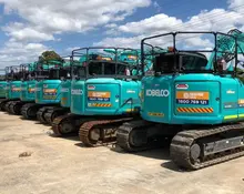 Row of excavators at a construction site, highlighting equipment readiness and safety for barrier installation.