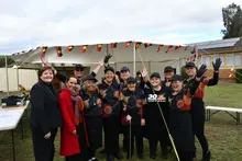  Group of people posing for a photo in front of a mobile home and tent, highlighting a community or outdoor event.